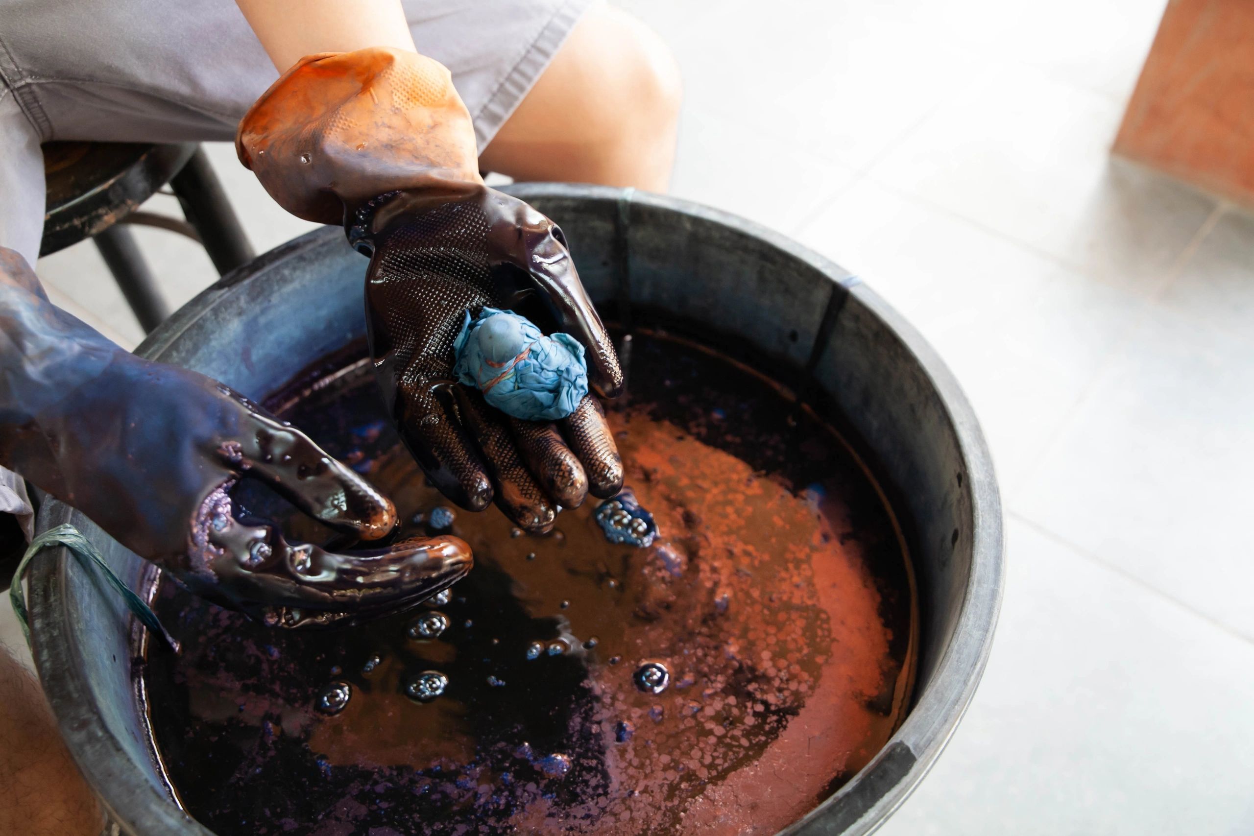 Hands dyeing cotton fabric with indigo, representing thoughtful color and process