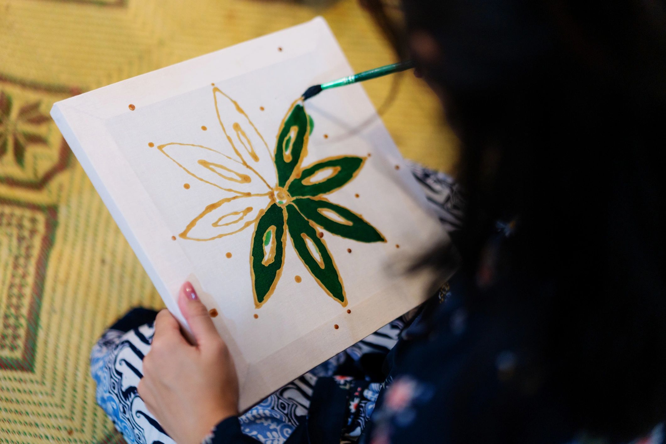 Artisan hand applying dye to patterned textile